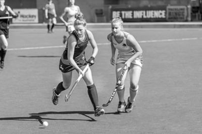 Two girls playing field hockey